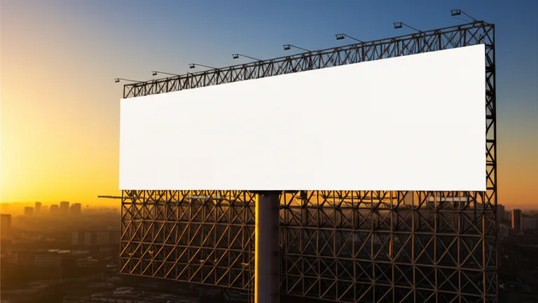 Estructura metálica de espectacular publicitario de gran formato al atardecer con cielo dramático y horizonte urbano