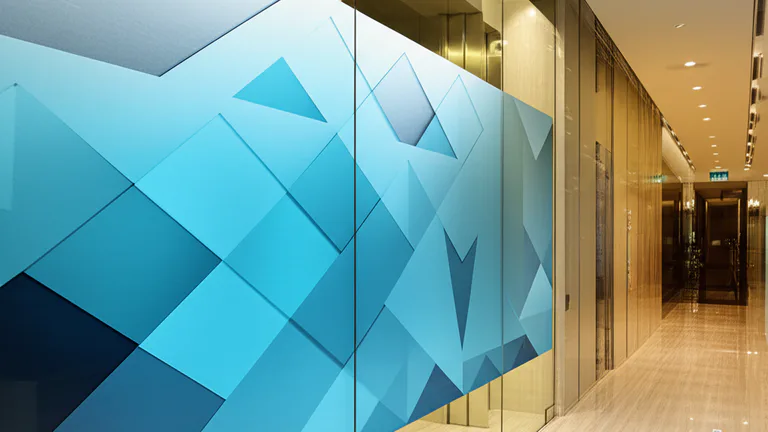 Puertas de cristal en elevador corporativo con vinil estático aplicado, mostrando diseño geométrico en oficina moderna