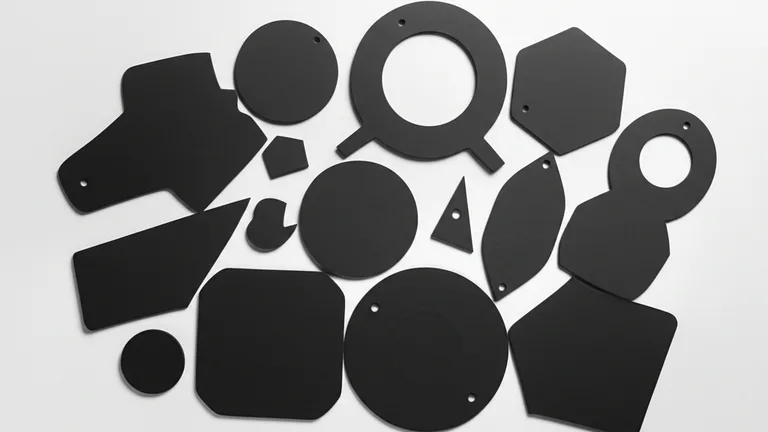 Vista cenital de danglers troquelados en distintas formas geométricas sobre superficie blanca, mostrando sustratos de poliestireno y cartón